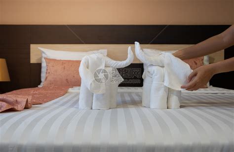 准备住宿美丽的近身手把白浴巾折叠起来像床单上的大象一样在床单上盖着白色浴巾高清图片下载-正版图片307984474-摄图网