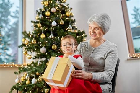 圣诞节、假期和家庭概念-快乐的祖母和小孙女在家里带着礼品盒。人物特写老年人高清摄影大图-千库网