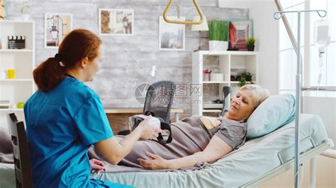 养老院的女护士给一位残疾老妇人一个VR耳机高清图片下载-正版图片503664057-摄图网