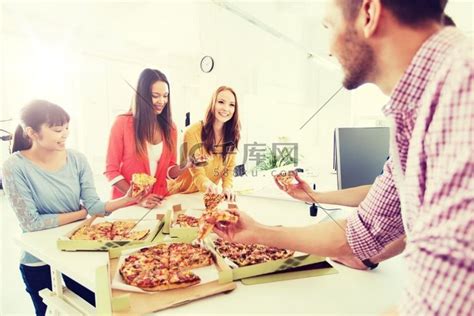 商业、食品、午餐和人的概念-快乐的国际商业团队在办公室吃披萨。高清摄影大图-千库网