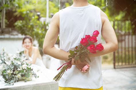 情人节白天一对情侣户外把玫瑰花藏在身后摄影图配图高清摄影大图-千库网