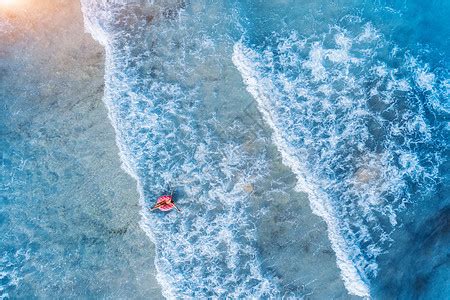 鸟瞰年轻的女人游泳与粉红色甜甜圈游泳环清澈的蓝色海洋与美丽的波浪日落夏天热带高清图片下载-正版图片300877719-摄图网