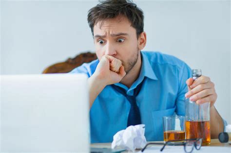拿着酒瓶喝酒的男子坐在桌前看他的笔记本电脑震惊图片下载 - 觅知网