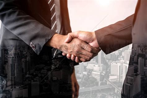 商务人士在城市办公楼握手的双重曝光图像背景显示商业交易的成功企业团队信任伙伴和工高清图片下载-正版图片506218176-摄图网