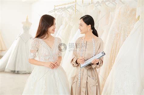 婚纱店内整理婚纱的婚礼策划师形象高清图片下载-正版图片502044489-摄图网
