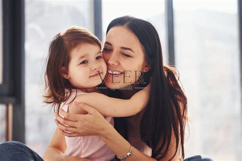 年轻的母亲和她的女儿在床上互相拥抱照片摄影图片_ID:401575853-Veer图库