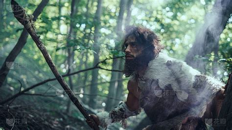 原始穴居人的肖像穿兽皮和毛皮狩猎与石尖矛在史前森林。史前穴居人猎人准备在丛林中投掷矛