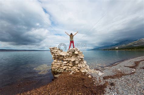 女孩双手举起站在一堆石头上高清图片下载-正版图片506135614-摄图网