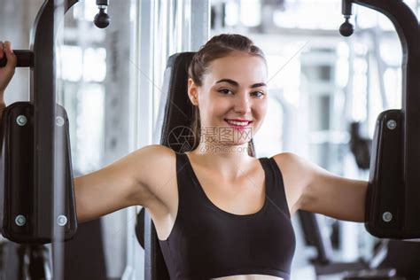 年轻有吸引力的健身女子在健身房用机器进行锻炼的电影基调高清图片下载-正版图片504510002-摄图网