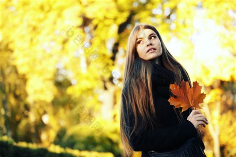 秋季女孩树木下拿着落叶图片-包图网