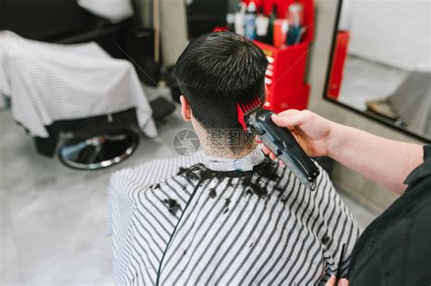 理发师在理发店为客户理发的特写照片男美发师的手与剪裁客高清图片下载-正版图片506516962-摄图网