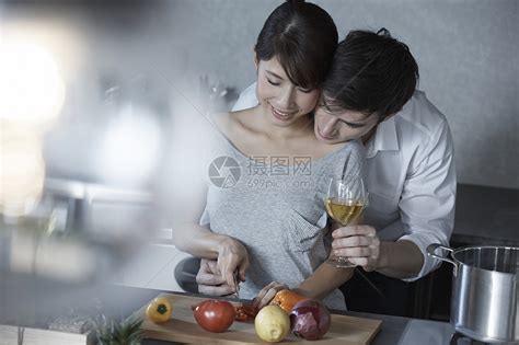 端着酒杯的男人搂着切菜的女人高清图片下载-正版图片502059857-摄图网