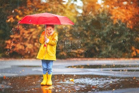 快乐的童女撑着伞，穿着胶靴在水坑里秋日漫步照片摄影图片_ID:309646257-Veer图库
