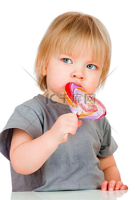 婴儿吃着白色背景上黏黏的棒棒糖。高清摄影大图-千库网
