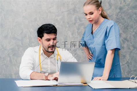 快乐的医生和护士在医院办公室使用笔记本电脑工作。上衣情侣装高清摄影大图-千库网