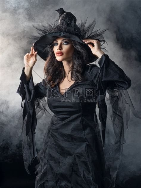 美丽的女人在万圣节女巫服装和帽子在雾中。高清摄影大图-千库网