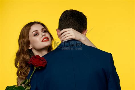恋人手里拿着红玫瑰拥抱黄色背景浪漫关系爱情家庭高清摄影大图-千库网