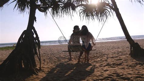 年轻浪漫的情侣一起坐在热带海滩的秋千上拥抱情侣在暑假期间在异国情调的海洋岸上放松和亲吻假日高清图片下载-正版图片503607631-摄图网