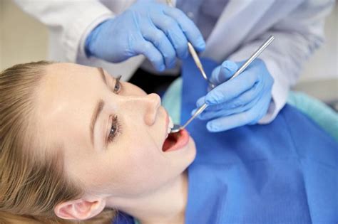 检查病人的口腔的牙科医生图片-牙医在牙科医生的椅子上检查病人的口腔素材-高清图片-摄影照片-寻图免费打包下载