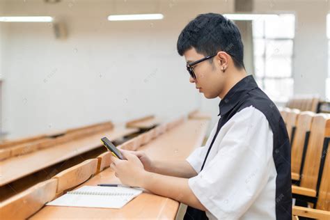 教室里玩手机的男大学生高清摄影大图-千库网