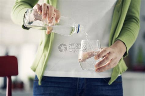 女人从瓶子里倒水到玻璃杯里高清图片下载-正版图片502796414-摄图网