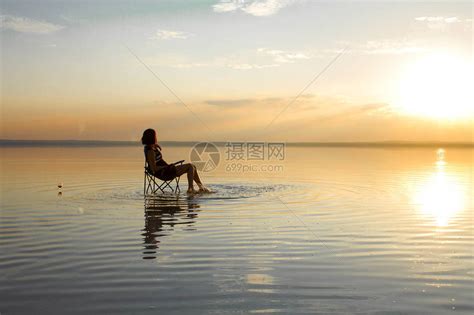 日落时妇女在海边坐高清图片下载-正版图片503804502-摄图网