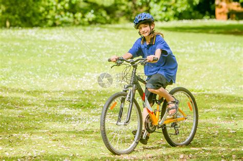 在自然公园背景下骑自行车的快乐青春期前男孩高清图片下载-正版图片507368549-摄图网