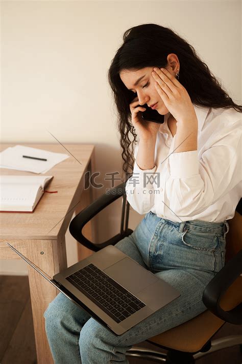 心烦意乱的疲惫女商人感到无聊，看着笔记本电脑慢性疲劳概念，并通过电话与家里的同事交谈。高清摄影大图-千库网