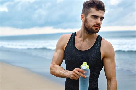 海边沙滩上拿水瓶的型男摄影图片 - 三原图库sytuku.com