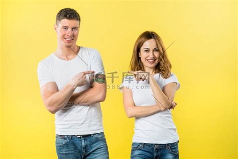 微笑的年轻夫妇互相指指点点看着相机短袖衫情侣装高清摄影大图-千库网