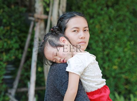 母亲把熟睡的小女孩抱在怀里。照片摄影图片_ID:159817233-Veer图库