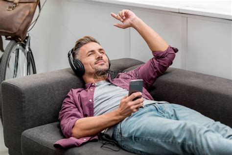 快乐的人躺在沙发上听音乐唱歌高清图片下载-正版图片502545113-摄图网