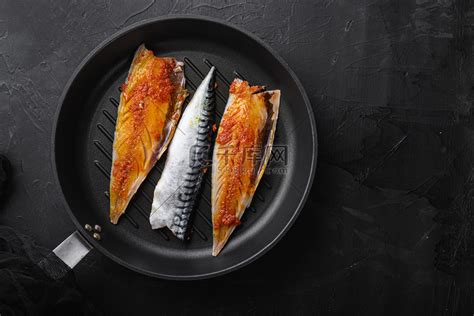 黑色背景煎锅上腌制的鲭鱼，平躺着，有文字空间高清摄影大图-千库网