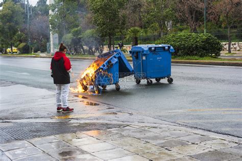 外部雅典市示威活动结束后一名女孩正在寻找着火烧毁的垃圾桶热灾难高清图片下载-正版图片307805850-摄图网