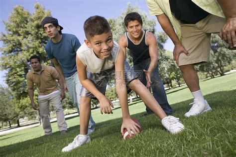 一个年轻男孩在公园里 和一群男人玩美式足球的肖像高清图片下载-正版图片321832657-摄图网