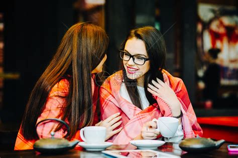 两个年轻美丽的女孩在阳台上闲聊喝杯咖啡高清图片下载-正版图片502771558-摄图网
