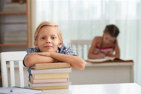 微笑的聪明孩子靠着一堆书看着摄像机高清图片下载-正版图片502665895-摄图网