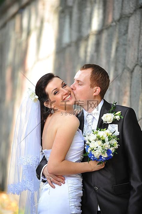 新娘和新郎在砖墙边接吻婚纱写真婚礼高清摄影大图-千库网
