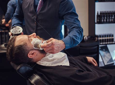 一名理发师在美发店为脸部刮胡须和涂高清图片下载-正版图片502659800-摄图网