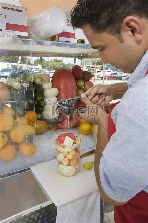 准备水果沙拉的男性摊贩高清摄影大图-千库网