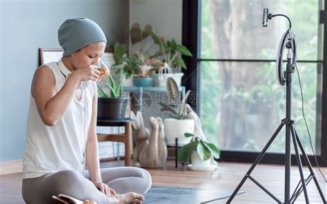 生病的博主亚洲癌症女在家庭健康与技术概念的网上视频流中喝茶时饮并使用网络视频流人们高清图片下载-正版图片307941459-摄图网
