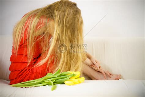 沙发上长着的可悲优雅女人沮丧疲劳有郁金香花束坐在沙发上有郁金香的优雅女人高清图片下载-正版图片305651876-摄图网