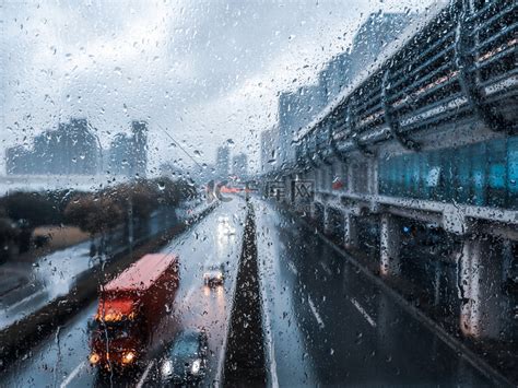 下雨天傍晚玻璃窗上雨滴窗外马路车流和车灯高清摄影大图-千库网