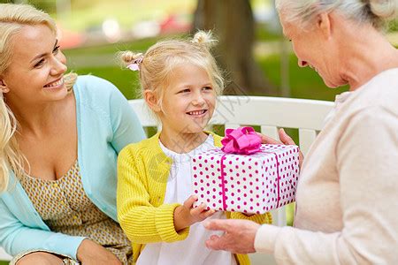 家庭,假期人的快乐的微笑孙女送礼物给她的祖母坐公园长凳上快乐的家庭公园给祖母送礼物高清图片下载-正版图片300431831-摄图网