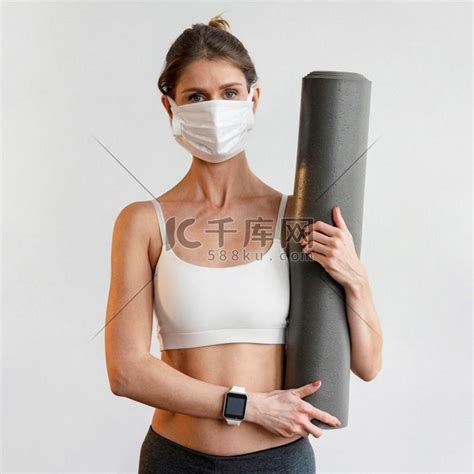 戴着医用口罩拿着瑜伽垫的前视女性高清摄影大图-千库网
