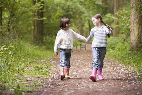 两姐妹牵着手微笑走在路上高清摄影大图-千库网