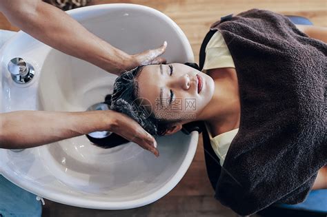 自信的理发师在店里用淋浴为顾客洗头时微笑高清图片下载-正版图片505389731-摄图网