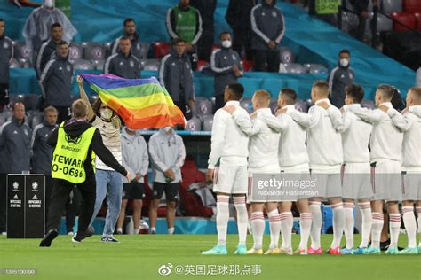 开赛前，一位德国队球迷举着彩虹旗冲进球场，并在球员面前展示……