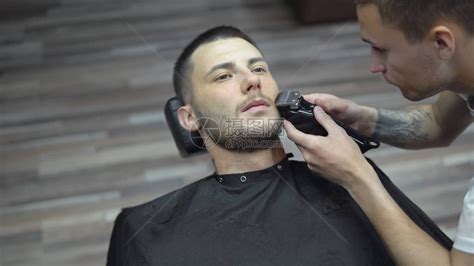 一个男人在美发沙龙剪一个时髦发型的特写镜头为客户服务的男白种人美发师留着胡子的男人用打字高清图片下载-正版图片506040998-摄图网
