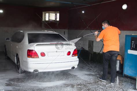 年轻人在洗车场用水洗一辆白色汽车高清图片下载-正版图片504362198-摄图网